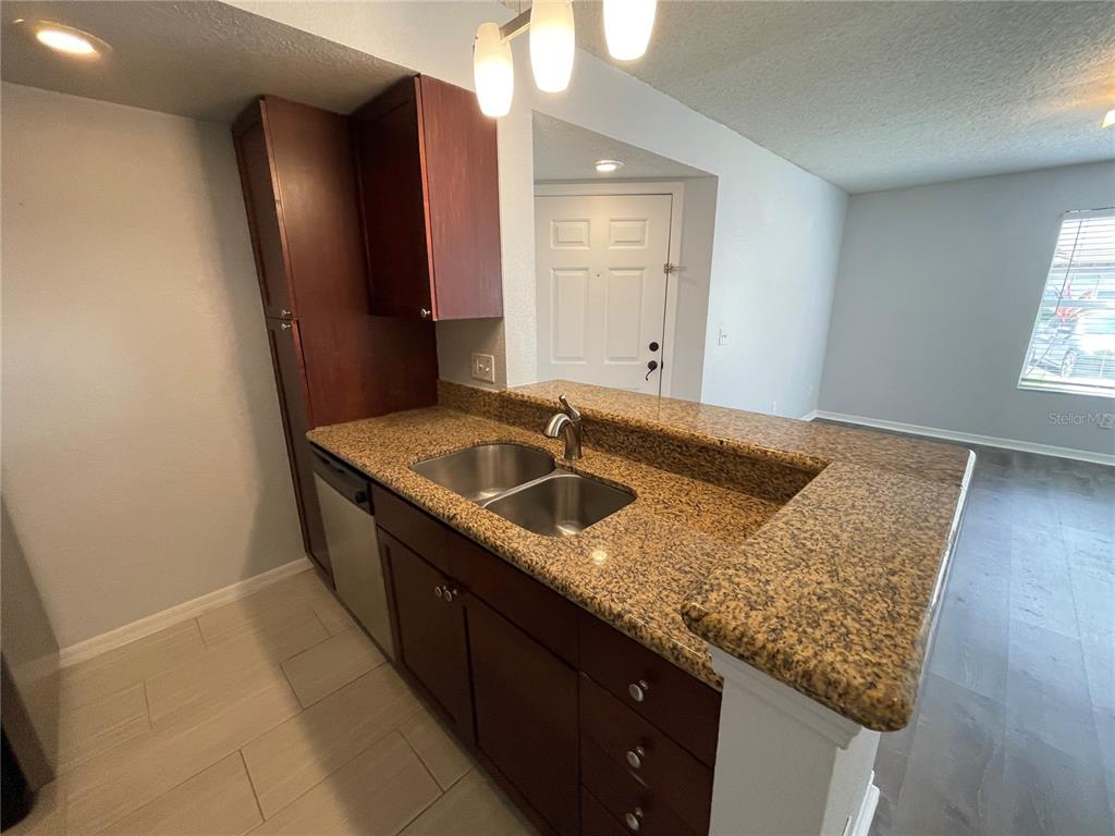 5128 Conroy Road, Unit 13 Orlando, FL 32811 - Photo 8 of 25 a kitchen with granite countertop sink and refrigerator