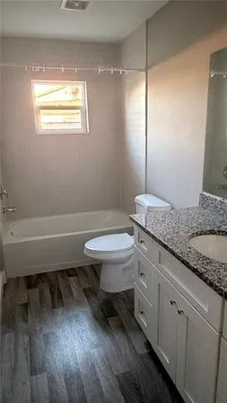 a bathroom with a granite countertop toilet sink and mirror