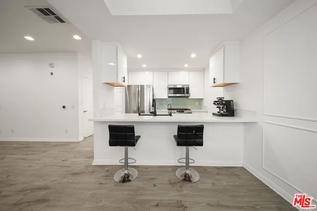 a view of kitchen with stainless steel appliances refrigerator stove microwave and cabinets