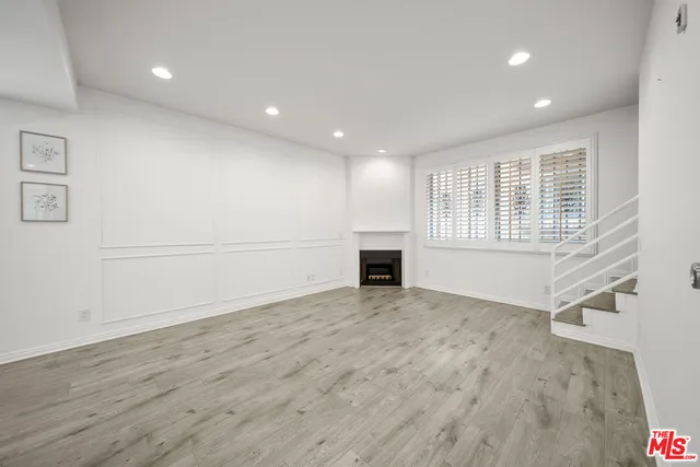 an empty room with wooden floor and fireplace
