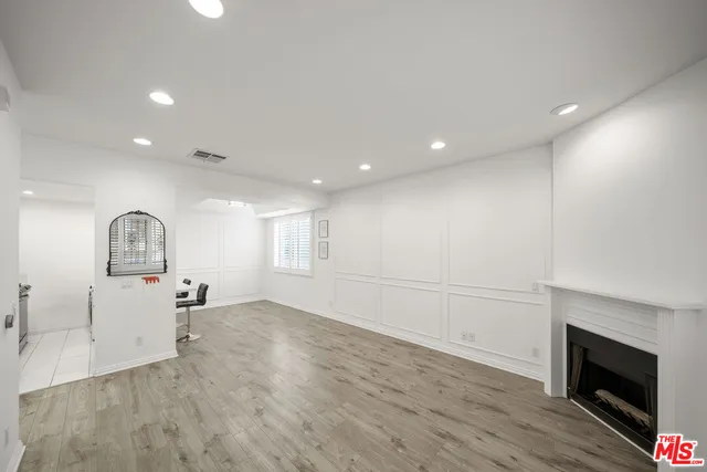 a view of empty room with a fireplace and wooden floor