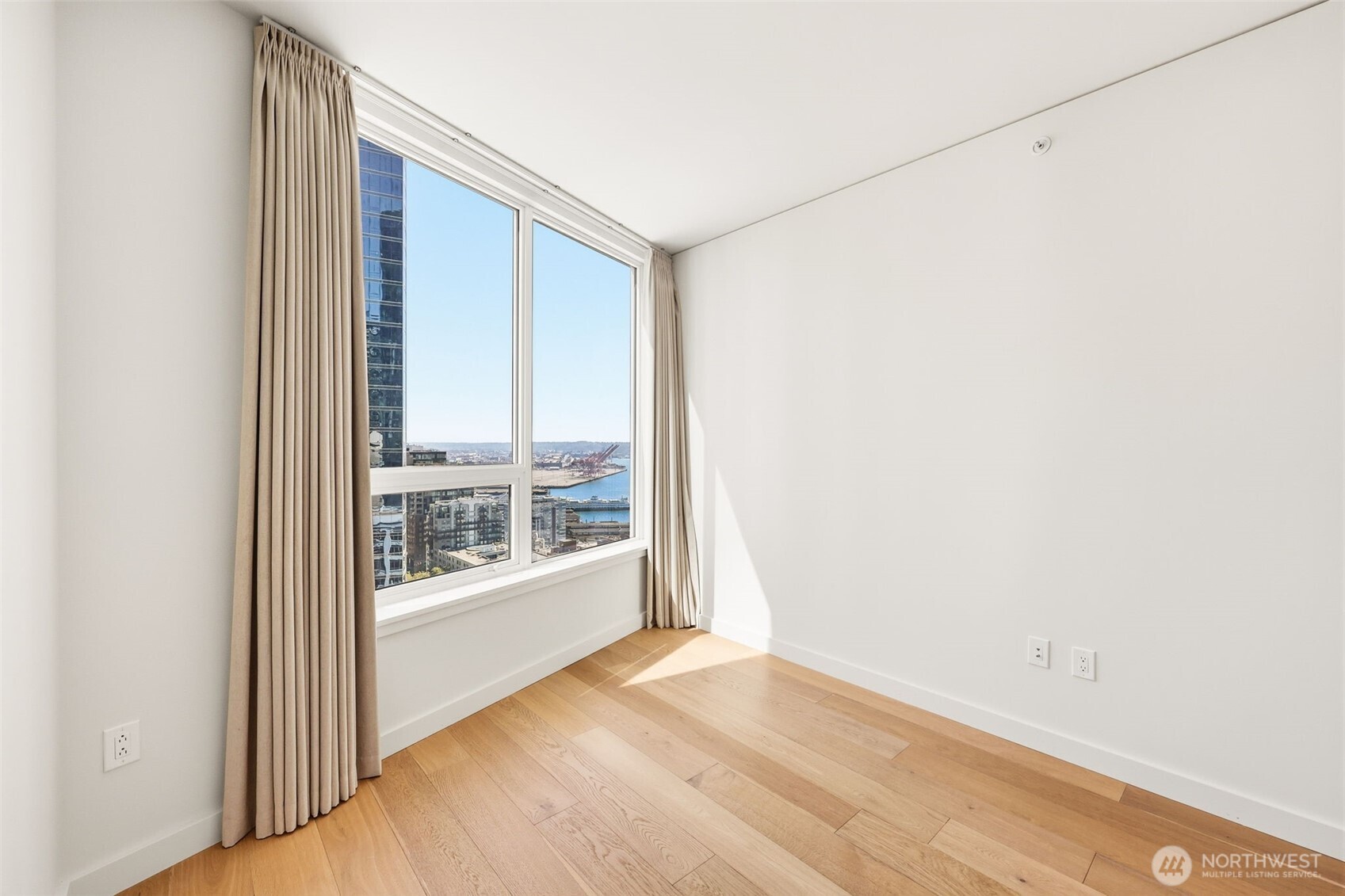 121 Stewart Street, Unit 1803 Seattle, WA 98101 - Photo 13 of 28 an empty room with wooden floor and windows