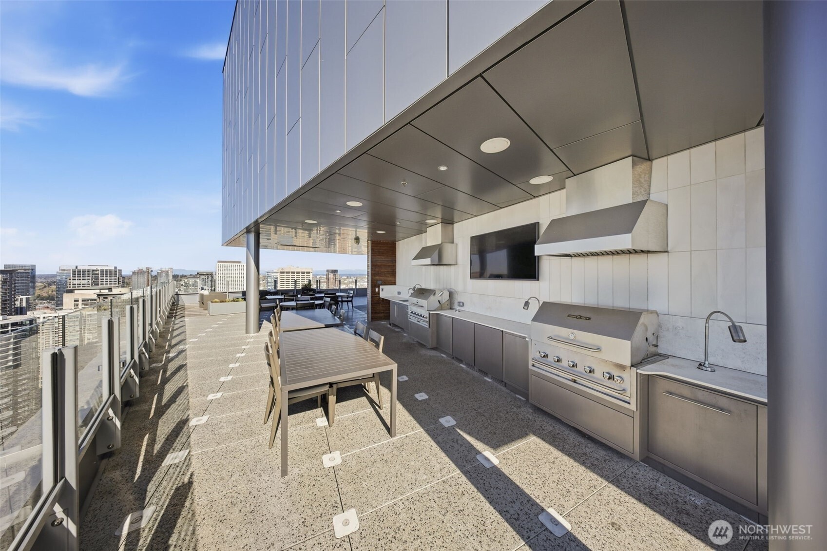 121 Stewart Street, Unit 1803 Seattle, WA 98101 - Photo 19 of 28 a kitchen with stainless steel appliances wooden floor dining table and chairs