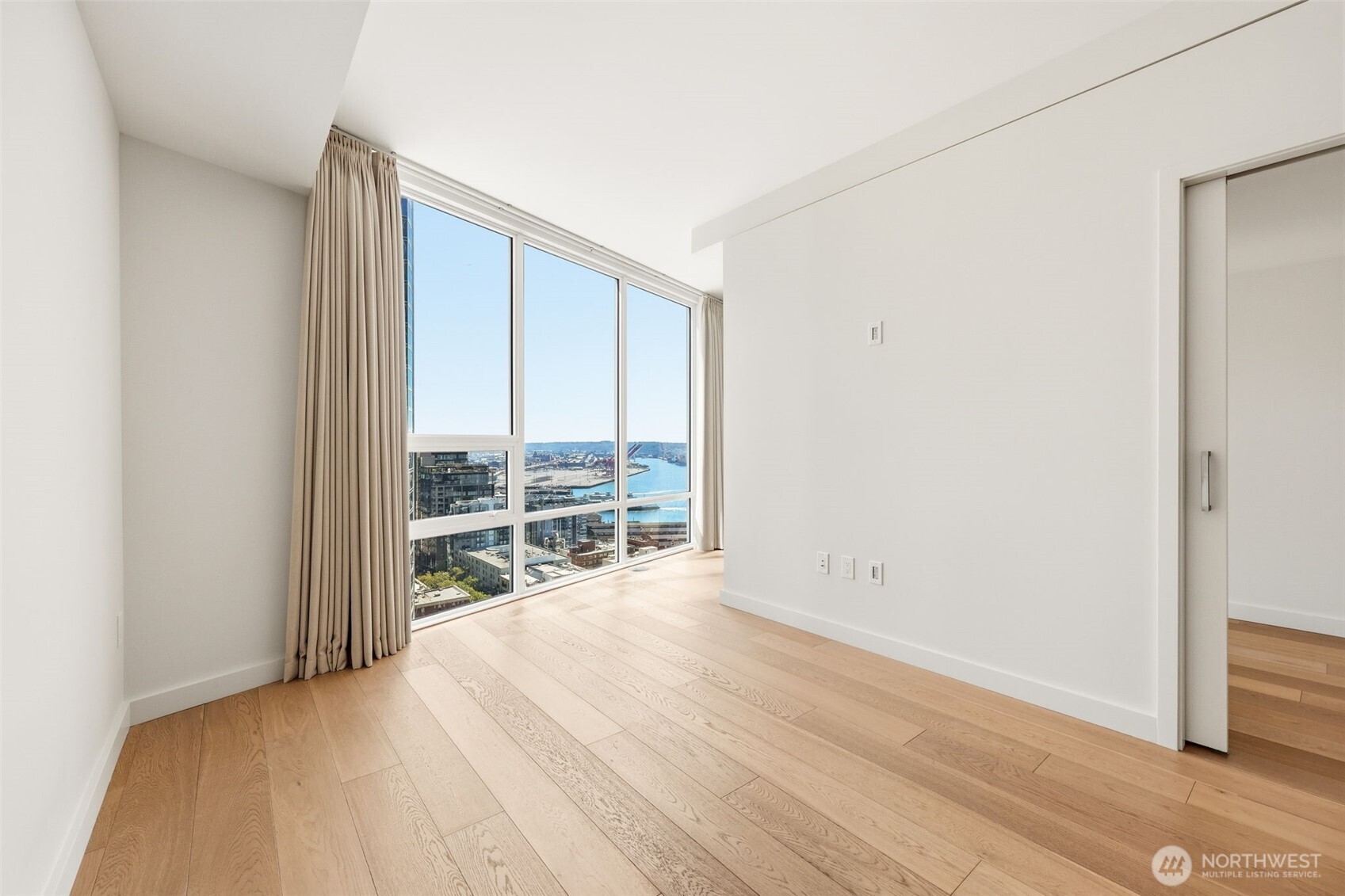 121 Stewart Street, Unit 1803 Seattle, WA 98101 - Photo 5 of 28 an empty room with wooden floor and windows