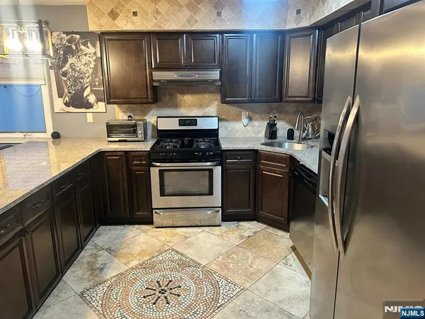 a kitchen with stainless steel appliances granite countertop a stove a sink and a refrigerator