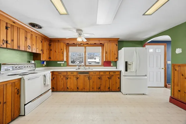 a kitchen with granite countertop a refrigerator a stove a sink dishwasher and white cabinets with wooden floor