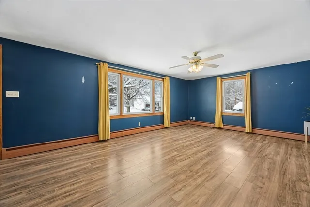 a view of an empty room with window and wooden floor
