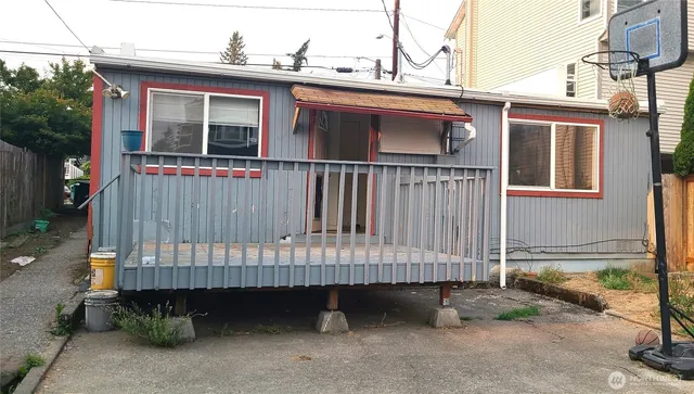 a view of a small wooden house with a small yard and wooden fence