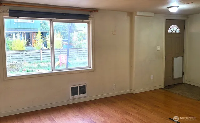 a view of an empty room with wooden floor and a window