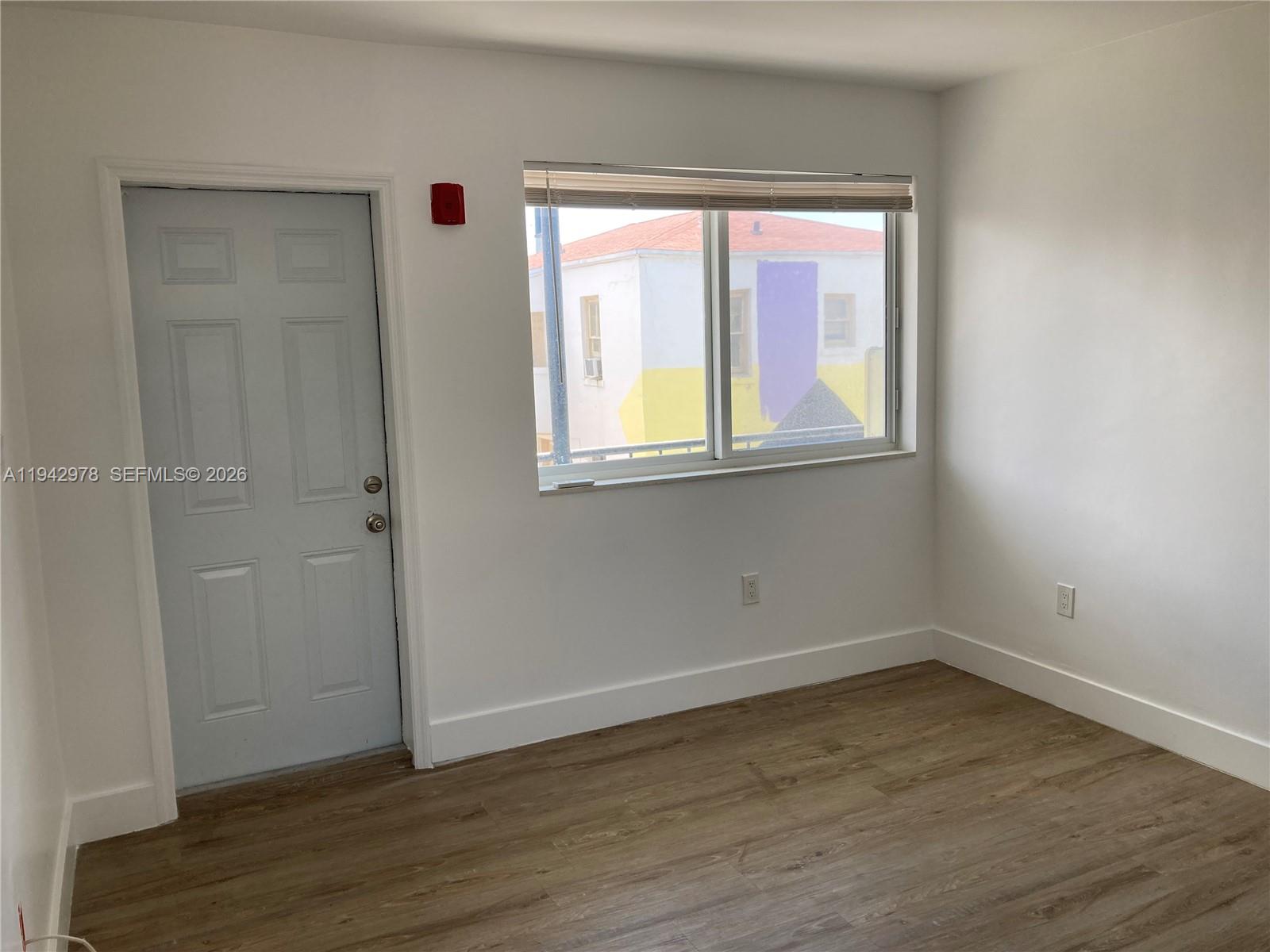 1815 Northwest 1st Court, Unit 2 Miami, FL 33136 - Photo 2 of 12 a view of an empty room with wooden floor and a window