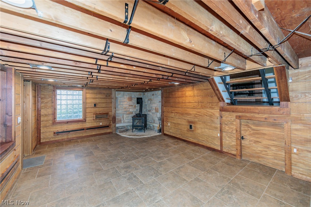 38565 Sugar Ridge Road North Ridgeville, OH 44039 - Photo 37 of 49 Basement with wood walls, a wood stove, and dark tile flooring