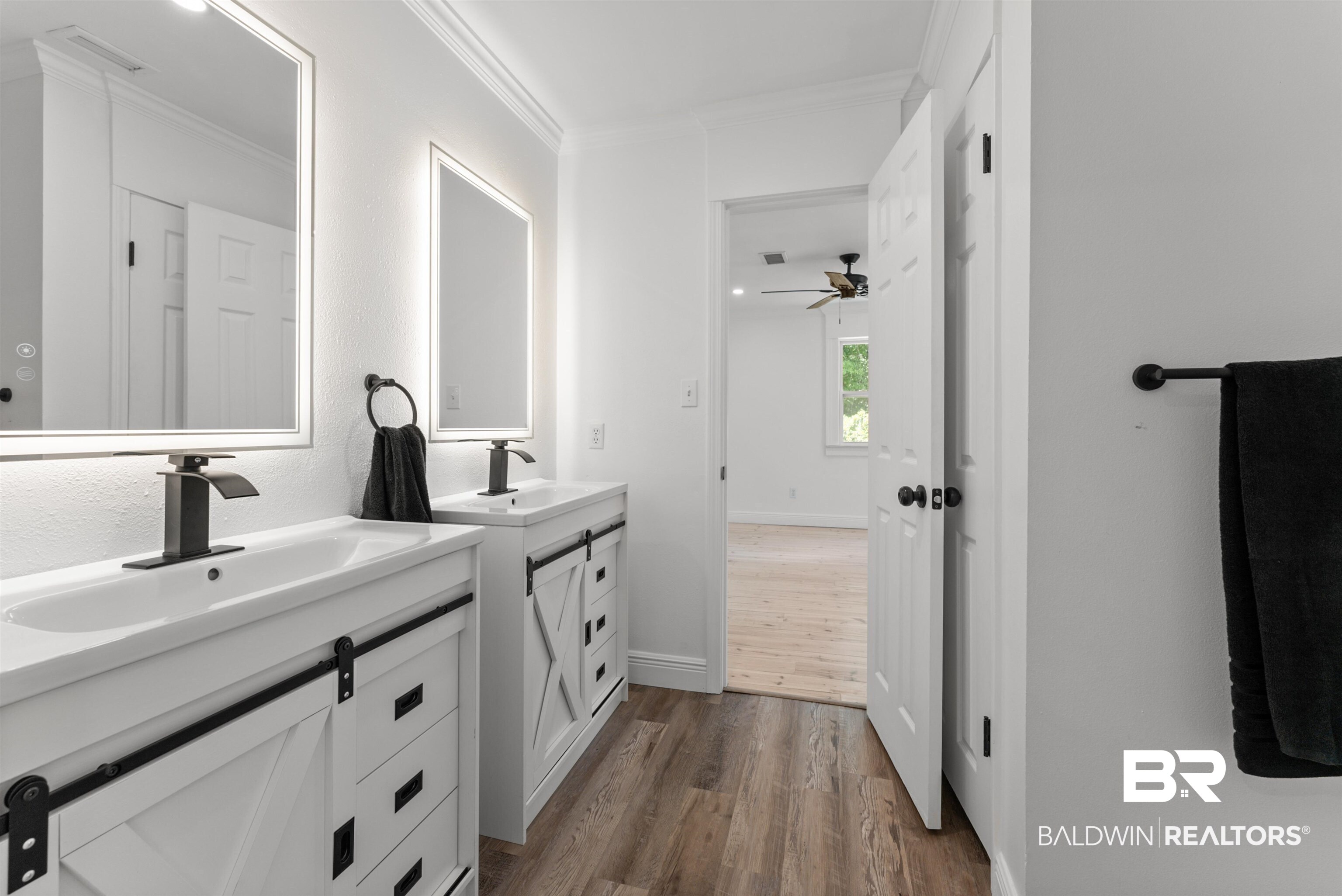 6447 Bemis Lane Bon Secour, AL 36511 - Photo 52 of 62 Dual vanities featuring integrated sinks, matte black fixtures, backlit mirrors, and farmhouse-style cabinetry with sliding barn door panels