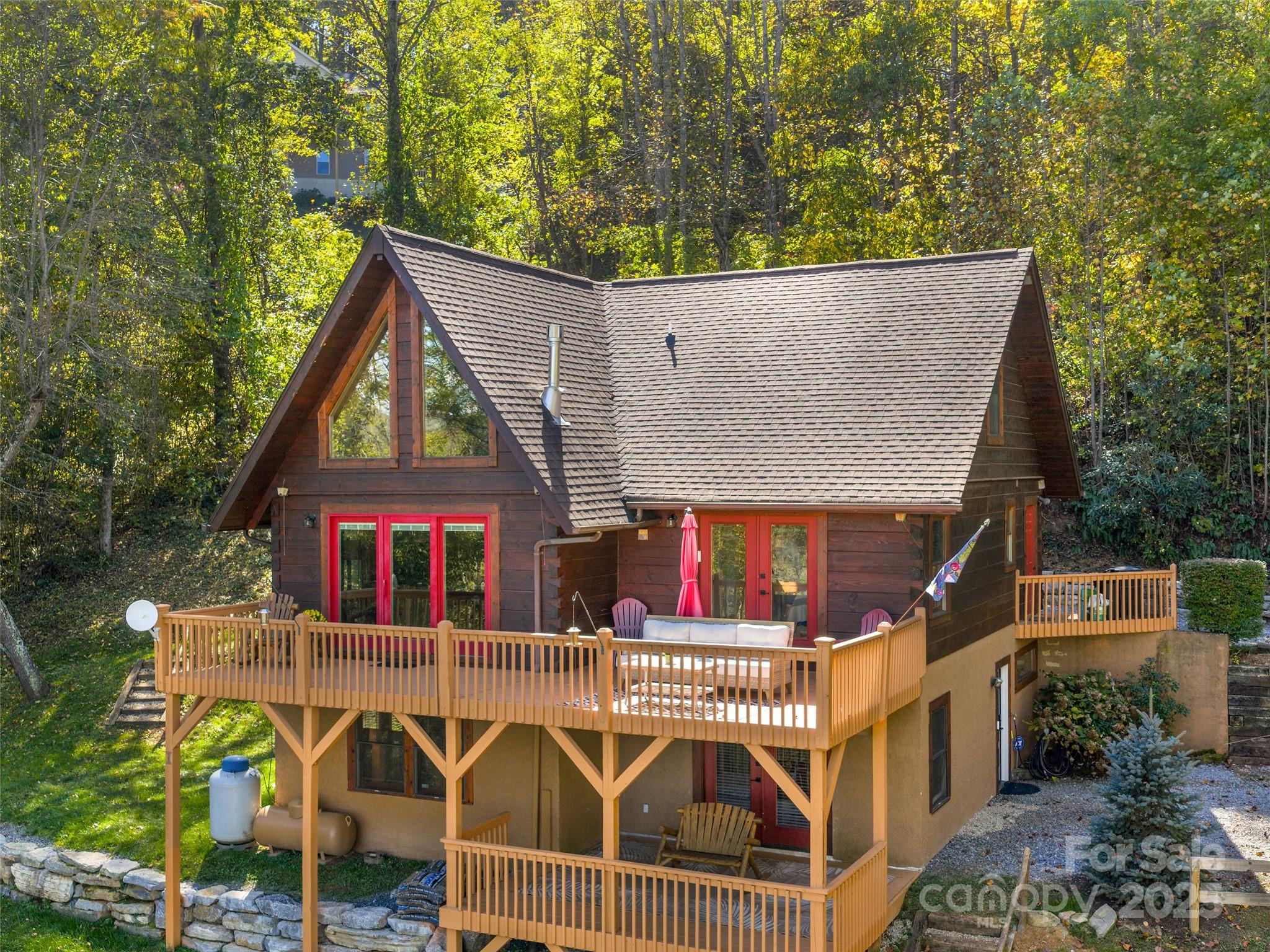67 Calhoun Ridge Drive Waynesville, NC 28786 - Photo 5 of 39 a view of a white house with large windows and a small yard