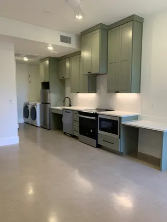a large kitchen with stainless steel appliances a stove a sink a refrigerator and a cabinets