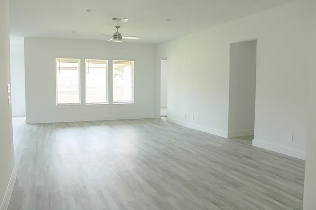 an empty room with wooden floor and windows