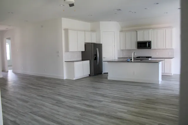 a kitchen with granite countertop a refrigerator and a stove top oven