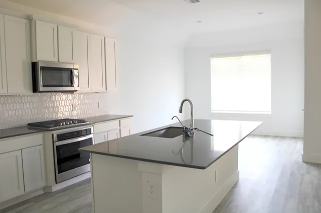 a kitchen with granite countertop a sink and a stove top oven