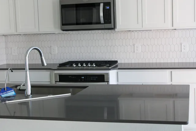 a kitchen with stainless steel appliances granite countertop a stove a microwave and a sink