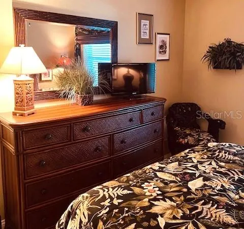 a bedroom with a bed and a lamp on dresser