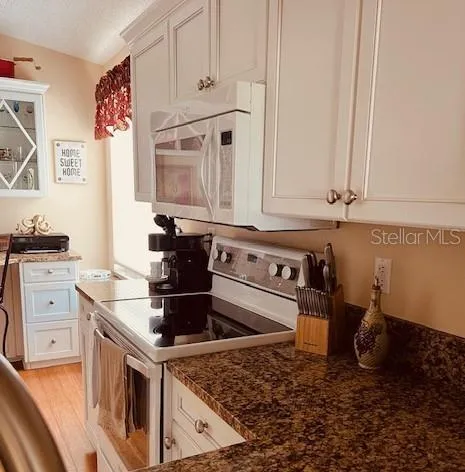 a kitchen with white cabinets and sink