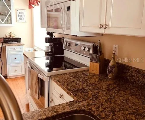 a kitchen with granite countertop a sink a stove and cabinets