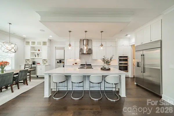a kitchen with stainless steel appliances kitchen island granite countertop a table chairs stove and white cabinets