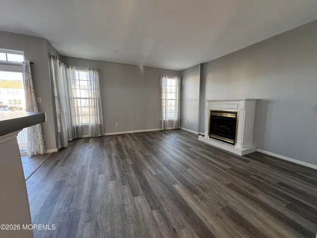 an empty room with wooden floor fireplace and windows