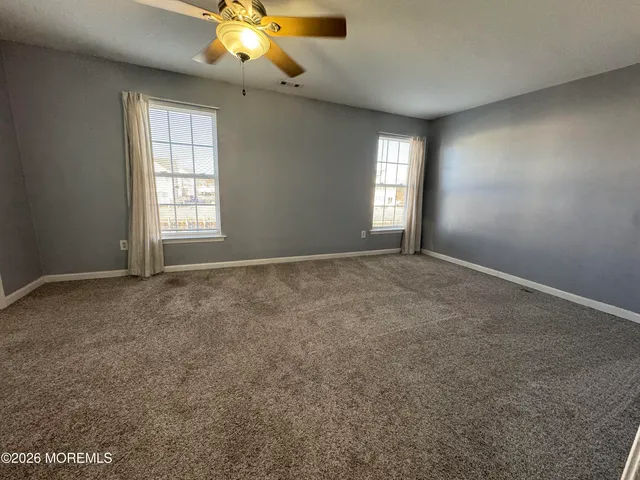 an empty room with windows and chandelier fan