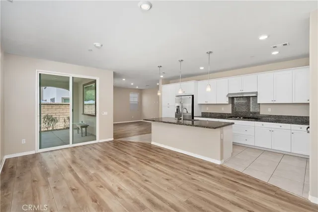 a large kitchen with stainless steel appliances a large counter top a stove and a refrigerator