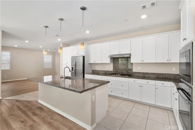 a kitchen with kitchen island granite countertop a sink a counter top space appliances and cabinets