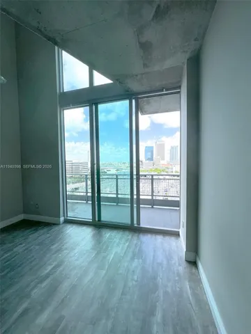 an empty room with wooden floor and balcony
