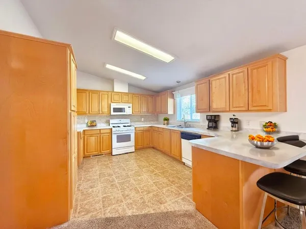 a kitchen with stainless steel appliances a sink a stove a refrigerator cabinets and a window