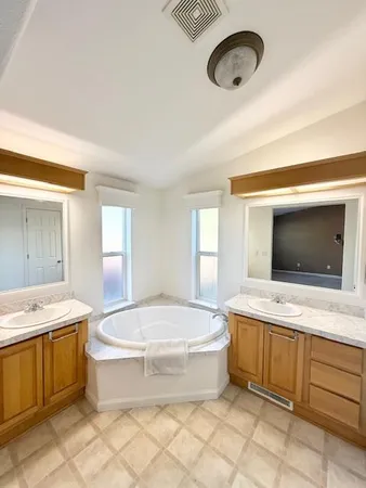 a spacious bathroom with a tub sink mirror and toilet
