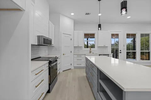 a large kitchen with stainless steel appliances granite countertop a sink stove and refrigerator