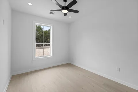 an empty room with a window and a ceiling fan