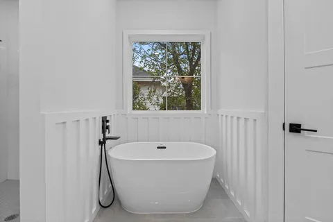 a white bath tub sitting in a bathroom next to a window