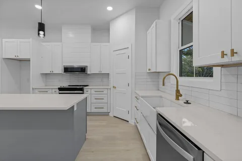 a kitchen with stainless steel appliances a sink stove and cabinets