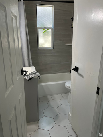 857 27th Street Ogden, UT 84403 - Photo 7 of 20 Bathroom featuring a white bathtub, gray tiled walls, white hexagonal floor tiles, and a privacy window