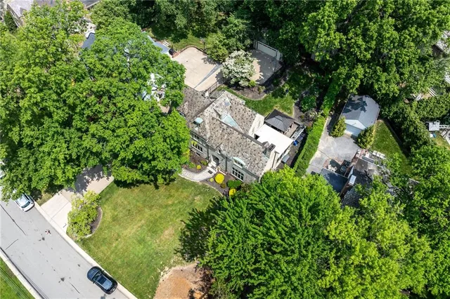 an aerial view of residential house with outdoor space and trees all around