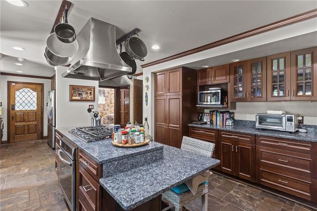 a kitchen with stainless steel appliances granite countertop a stove a sink dishwasher and a dining table with wooden floor