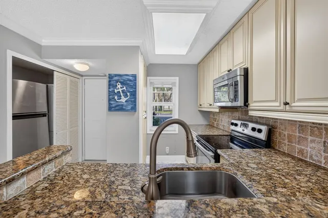 a kitchen with granite countertop a sink and a refrigerator