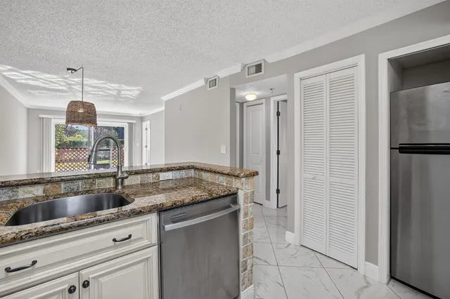 a kitchen with stainless steel appliances granite countertop a sink and a refrigerator