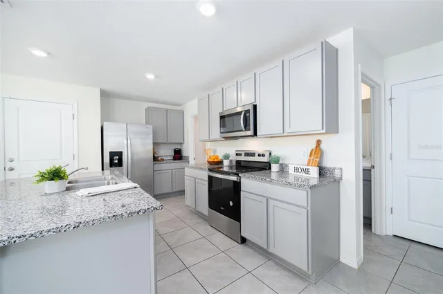 a kitchen with granite countertop a sink stainless steel appliances and white cabinets
