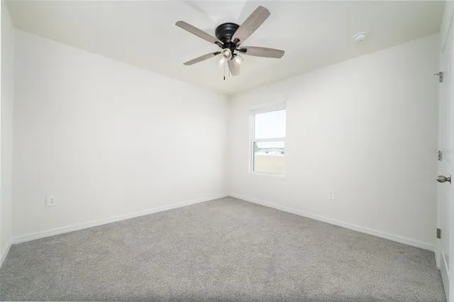 an empty room with a ceiling fan and a window