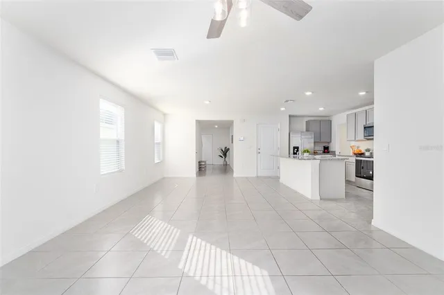 a view of open kitchen with white cabinets and refrigerator