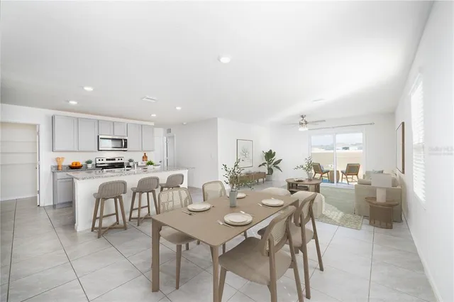 a view of a dining room and livingroom with furniture a rug a kitchen and view