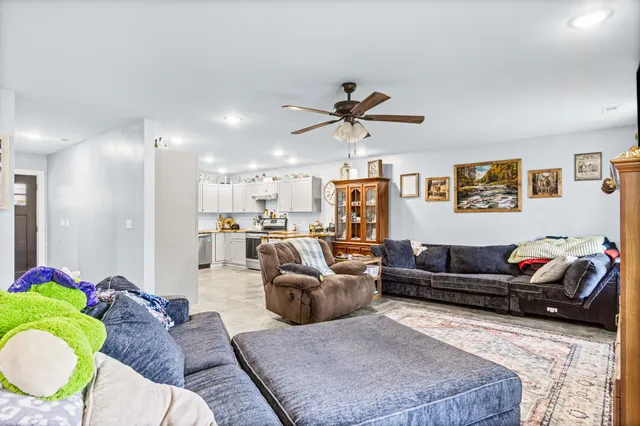 a living room with furniture kitchen view and a chandelier