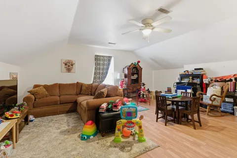 a living room with furniture a clock and a ceiling fan