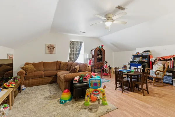 a living room with furniture a clock and a ceiling fan