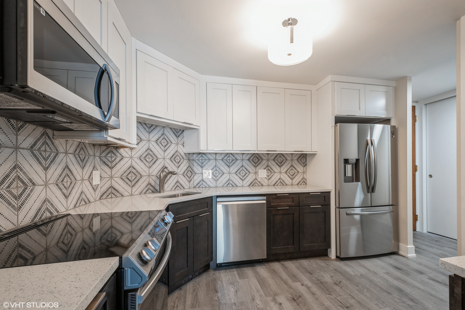 6033 North Sheridan Road, Unit 44D Chicago, IL 60660 - Photo 5 of 12 a kitchen with stainless steel appliances granite countertop a refrigerator a stove a sink and white cabinets with wooden floor